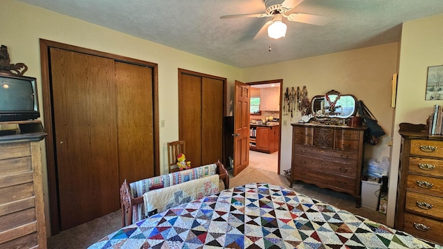 carpeted bedroom featuring multiple closets, ceiling fan, and a textured ceiling