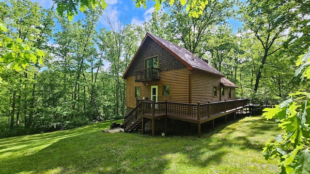rear view of house featuring a balcony, log veneer siding, a lawn, a deck, and stairs