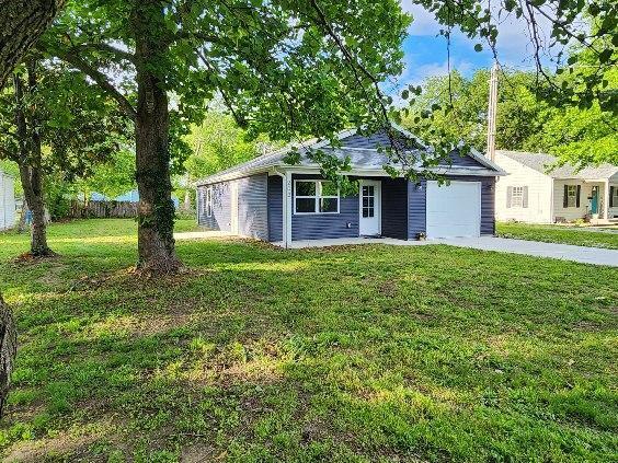 ranch-style house featuring a garage, a front lawn, and driveway