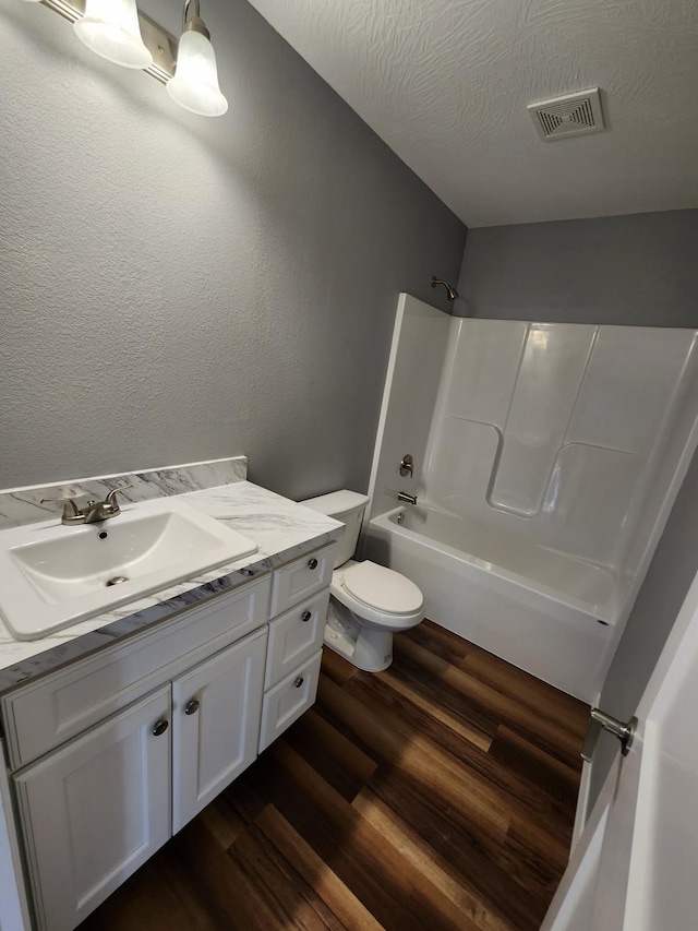 full bath featuring wood finished floors, toilet, vanity, and bathing tub / shower combination