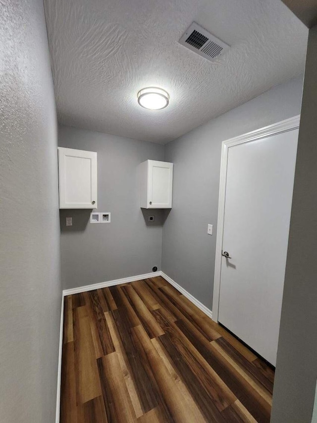washroom with cabinet space, electric dryer hookup, dark wood-type flooring, a textured ceiling, and washer hookup