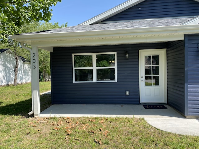 property entrance with a yard and a shingled roof