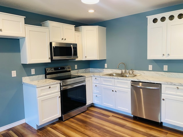 kitchen with appliances with stainless steel finishes, a sink, light countertops, recessed lighting, and white cabinetry