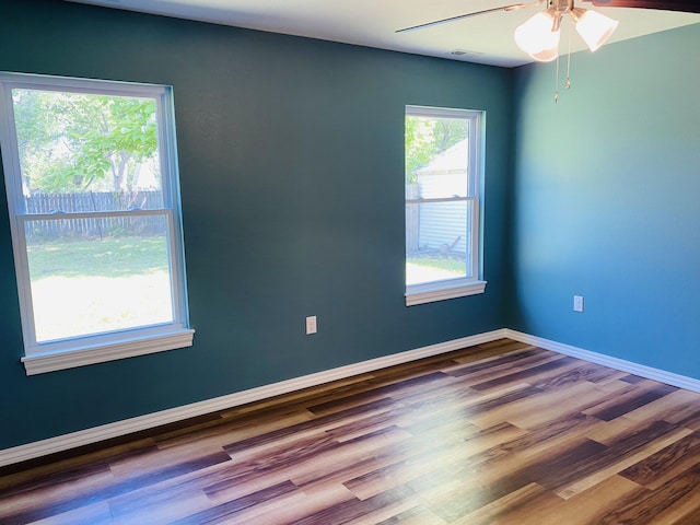 spare room with a ceiling fan, wood finished floors, and baseboards
