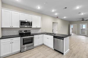 kitchen featuring stainless steel appliances, a peninsula, dark countertops, decorative backsplash, and recessed lighting
