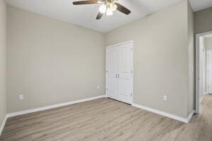 unfurnished bedroom featuring baseboards, wood finished floors, a closet, and a ceiling fan