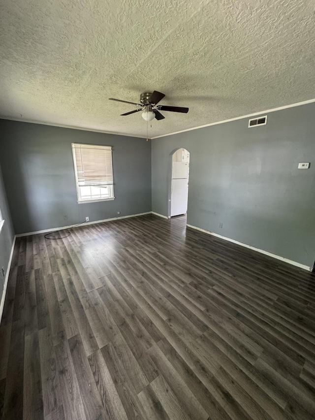 empty room with a ceiling fan, arched walkways, a textured ceiling, dark wood finished floors, and baseboards