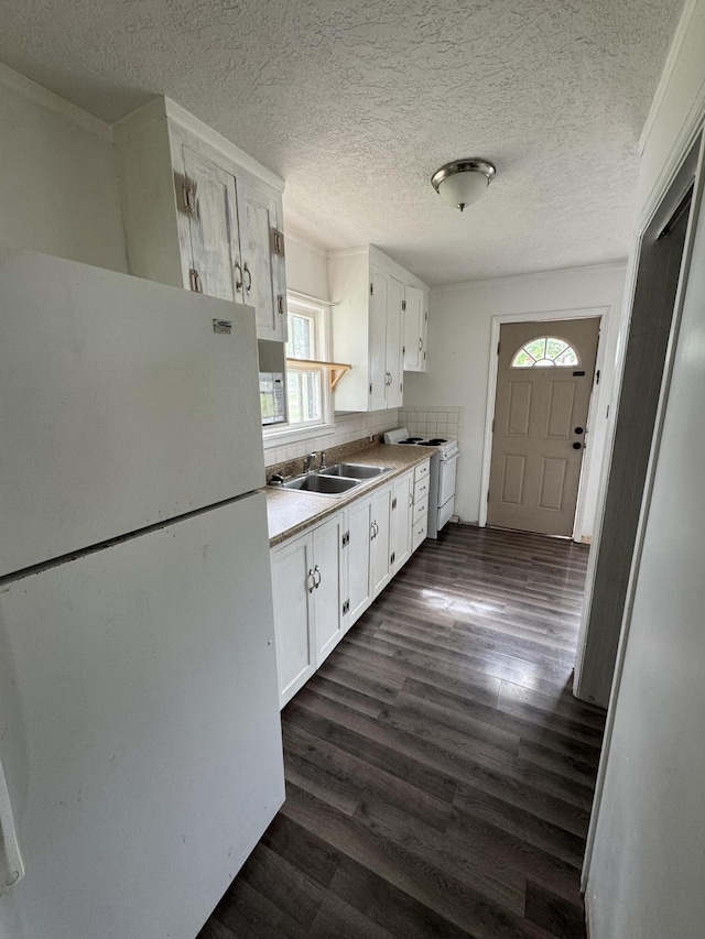 kitchen with white appliances, a sink, white cabinets, dark wood-style floors, and a textured ceiling