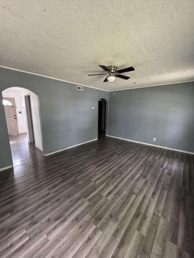 spare room with arched walkways, a ceiling fan, dark wood-style floors, and a textured ceiling