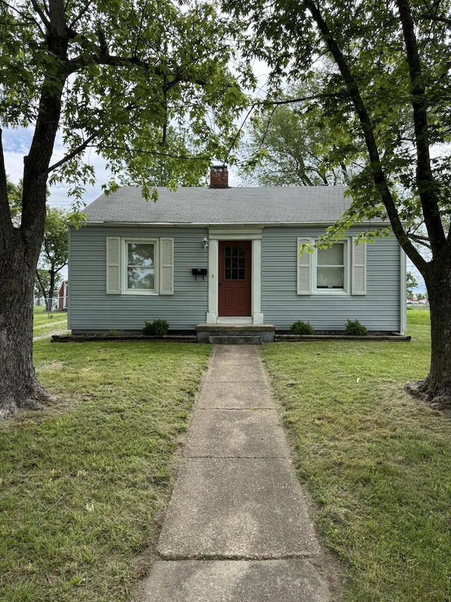 view of front facade with a chimney and a front lawn