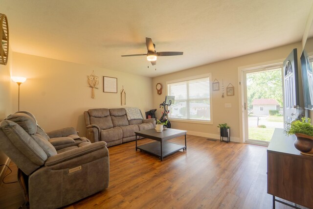 living area with a ceiling fan, wood finished floors, and baseboards