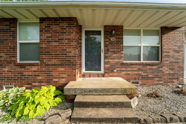 property entrance featuring brick siding and crawl space