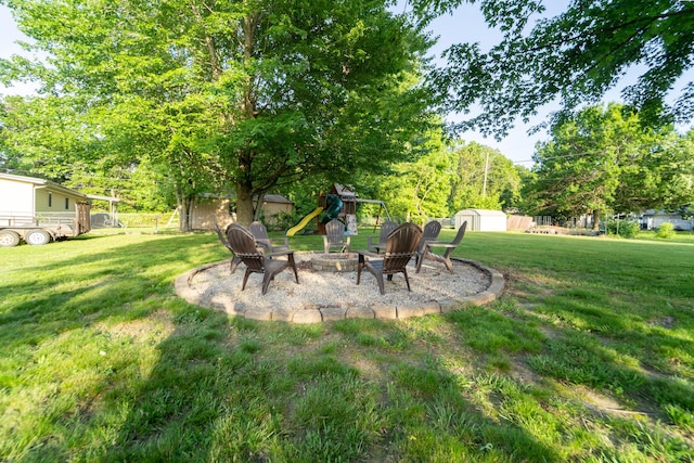 view of yard featuring an outdoor fire pit, a storage unit, a playground, and an outdoor structure