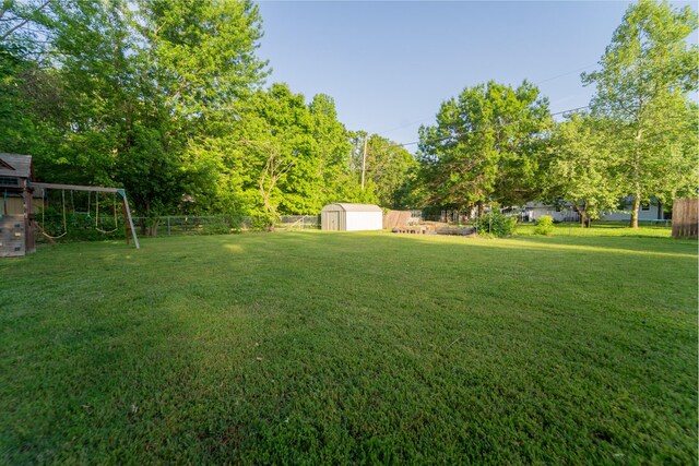 view of yard featuring a shed, a playground, and an outdoor structure
