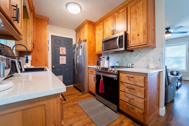 kitchen with stainless steel appliances, light wood-style flooring, and backsplash