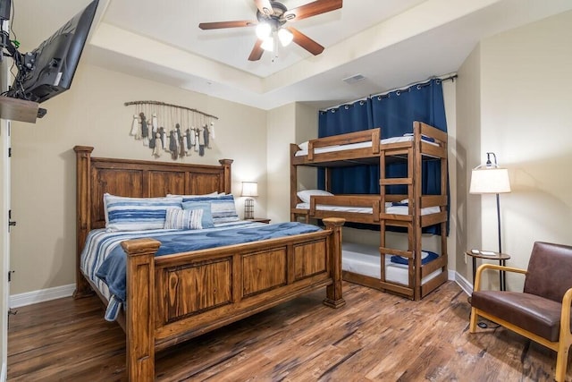 bedroom with wood finished floors, baseboards, a raised ceiling, and a ceiling fan