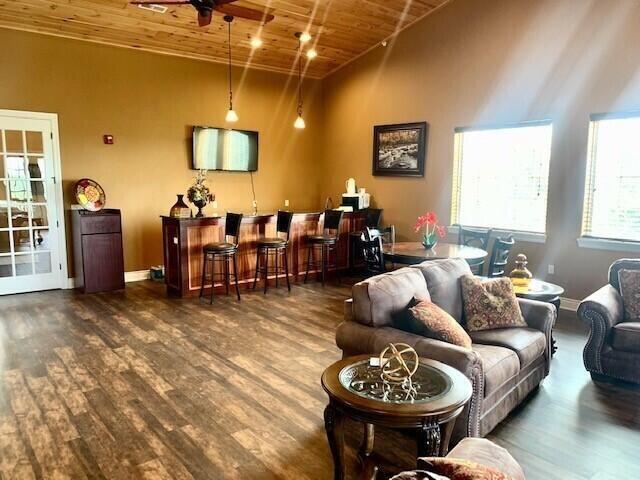 bar area with wood ceiling, wood finished floors, a ceiling fan, decorative light fixtures, and high vaulted ceiling