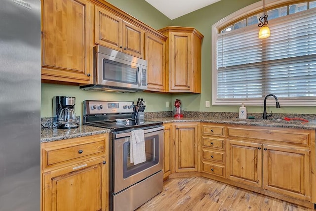 kitchen featuring appliances with stainless steel finishes, a sink, light wood-style floors, and plenty of natural light