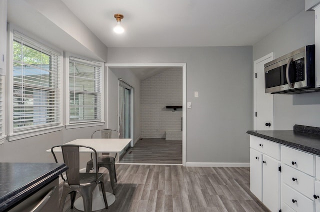 2857 E Linwood St, Springfield, MO 65804 - kitchen featuring stainless steel microwave, dark countertops, light wood-style flooring, white cabinets, and baseboards
