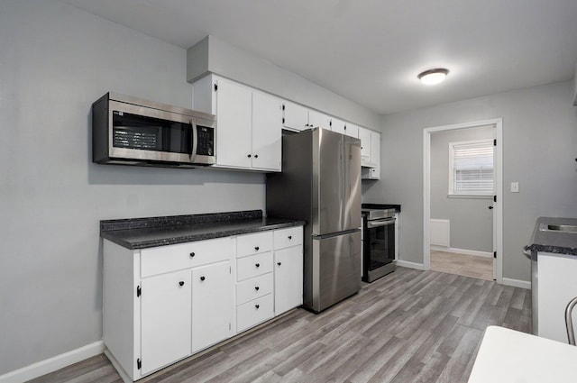 2857 E Linwood St, Springfield, MO 65804 - kitchen with appliances with stainless steel finishes, light wood finished floors, baseboards, white cabinetry, and dark countertops
