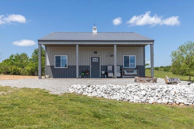 back of house with a yard, metal roof, and board and batten siding