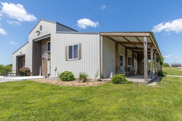 view of front of home with a front lawn, a detached garage, a patio area, and board and batten siding