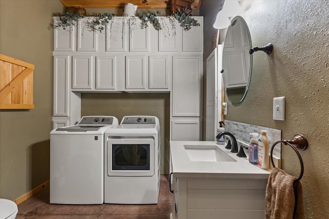 clothes washing area featuring washing machine and clothes dryer, baseboards, and cabinet space