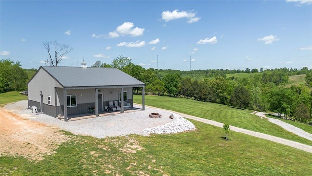 rear view of property featuring a fire pit, a yard, and metal roof
