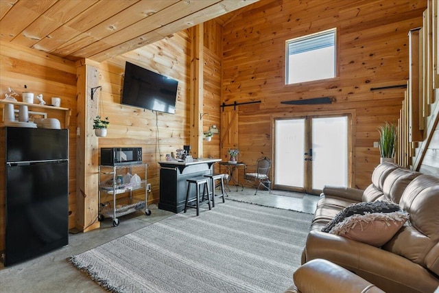 living area featuring healthy amount of natural light, wooden walls, concrete floors, french doors, and wooden ceiling