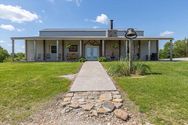 view of front facade featuring french doors, board and batten siding, a front yard, and metal roof