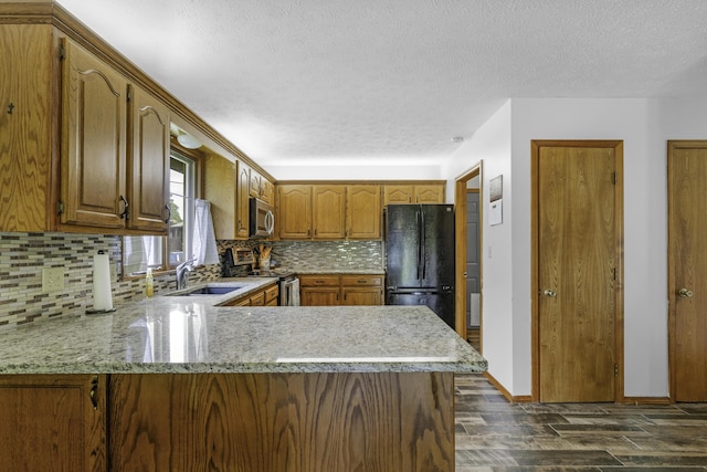 2515 S Laurel Ave, Springfield, MO 65807 - kitchen with stainless steel appliances, a sink, dark wood-style flooring, a peninsula, and decorative backsplash
