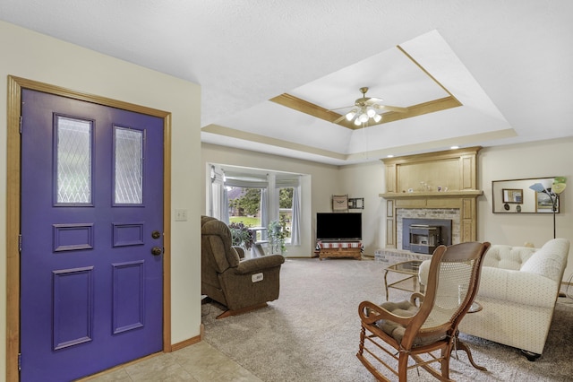 2515 S Laurel Ave, Springfield, MO 65807 - living area featuring a tray ceiling, a fireplace, a ceiling fan, light carpet, and baseboards