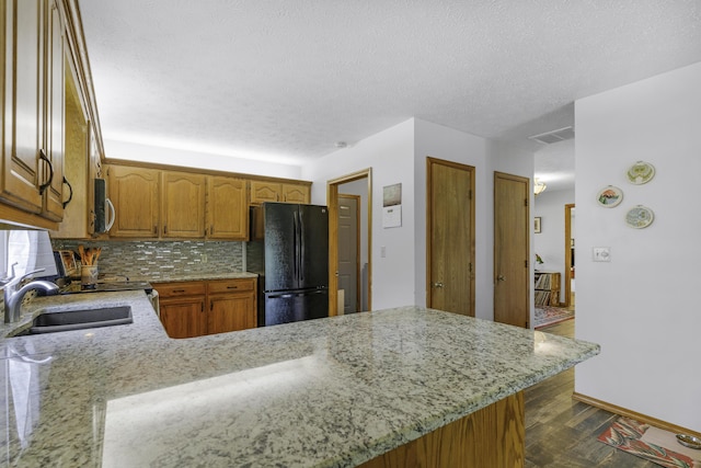 2515 S Laurel Ave, Springfield, MO 65807 - kitchen with freestanding refrigerator, a sink, stainless steel microwave, light stone countertops, and a textured ceiling