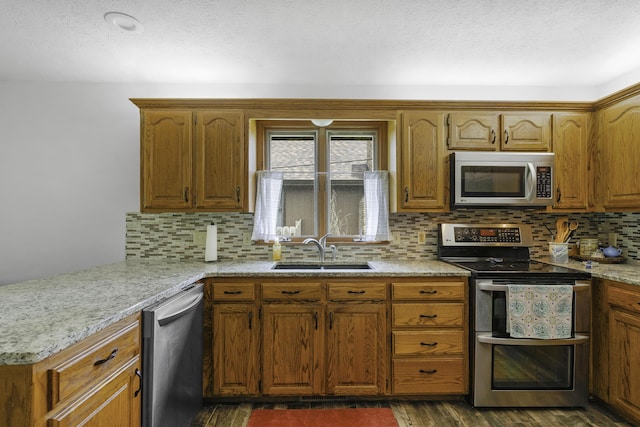 2515 S Laurel Ave, Springfield, MO 65807 - kitchen with stainless steel appliances, a sink, brown cabinets, dark wood-style flooring, and a textured ceiling