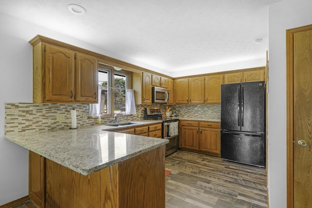 2515 S Laurel Ave, Springfield, MO 65807 - kitchen featuring stainless steel appliances, a peninsula, a sink, brown cabinets, and wood finished floors