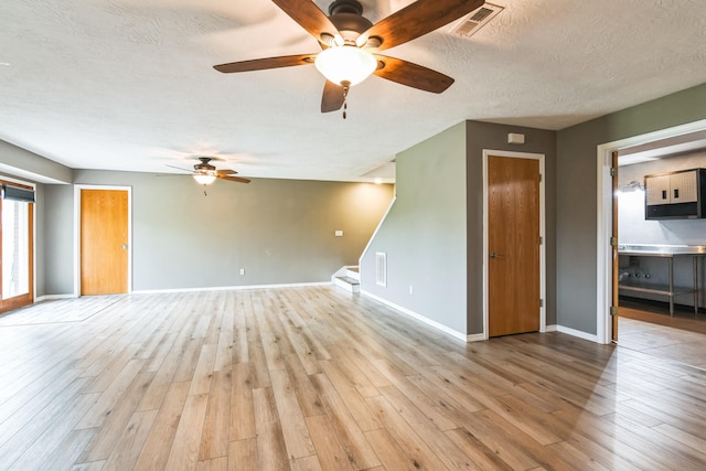 1888 S High Rdg, Nixa, MO 65714 - unfurnished living room with ceiling fan, stairway, light wood-type flooring, baseboards, and a textured ceiling