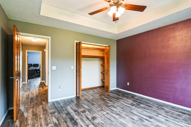 1888 S High Rdg, Nixa, MO 65714 - unfurnished bedroom featuring dark wood-type flooring, baseboards, a tray ceiling, a ceiling fan, and a closet