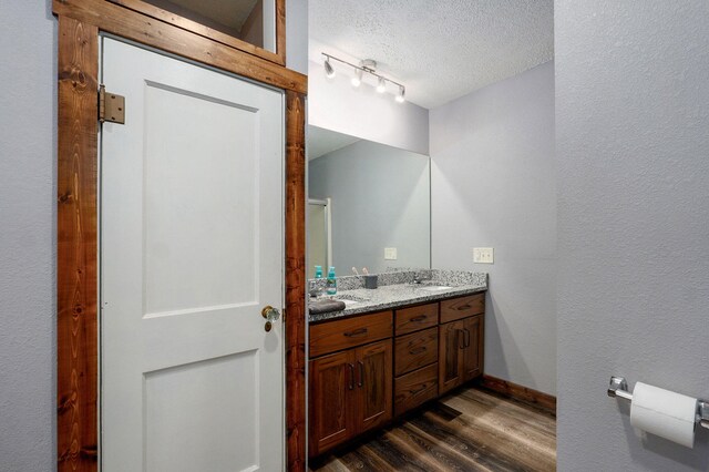 2121 E 505th Rd, Halfway, MO 65663 - bathroom with wood finished floors, double vanity, a textured ceiling, and baseboards