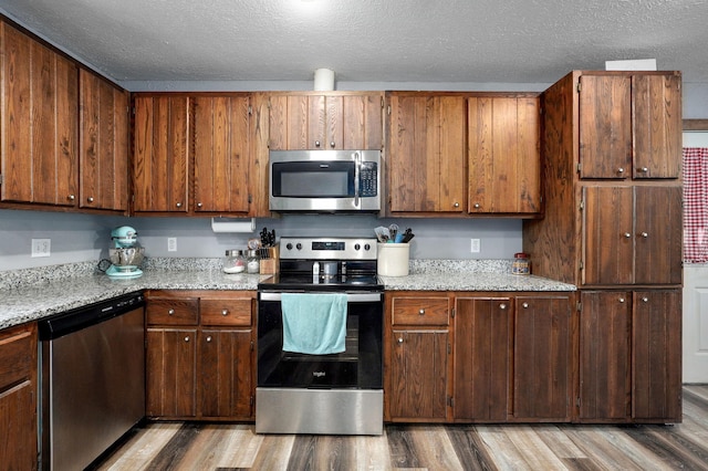 2121 E 505th Rd, Halfway, MO 65663 - kitchen featuring stainless steel appliances, light wood-style flooring, a textured ceiling, and light stone counters
