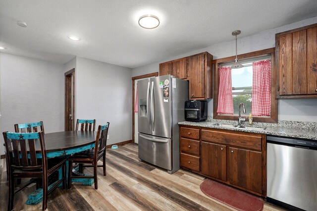 2121 E 505th Rd, Halfway, MO 65663 - kitchen featuring stainless steel appliances, a sink, light wood-style floors, hanging light fixtures, and light stone counters