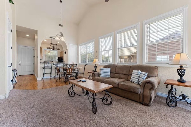 living area featuring arched walkways, carpet floors, baseboards, and high vaulted ceiling
