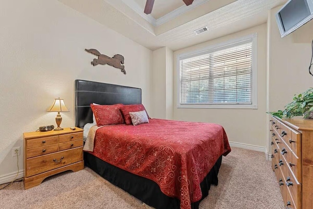 carpeted bedroom featuring a raised ceiling, baseboards, and a ceiling fan