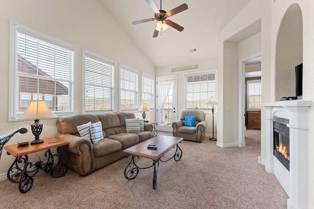 living area featuring carpet floors, a ceiling fan, vaulted ceiling, a glass covered fireplace, and baseboards