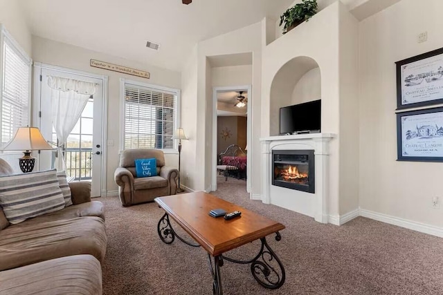 living room featuring carpet, ceiling fan, a glass covered fireplace, and plenty of natural light