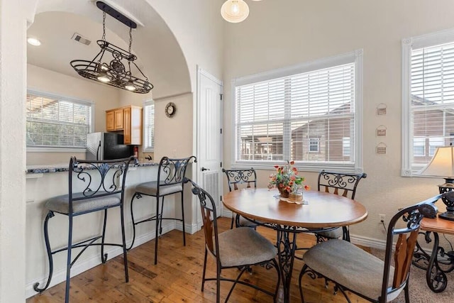dining room with wood-type flooring, baseboards, and arched walkways