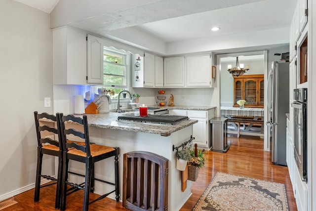 178 S Peach Tree Ln, Republic, MO 65738 - kitchen featuring a peninsula, appliances with stainless steel finishes, white cabinets, a chandelier, and backsplash