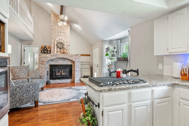 178 S Peach Tree Ln, Republic, MO 65738 - kitchen with a brick fireplace, appliances with stainless steel finishes, light wood-style floors, vaulted ceiling, and a peninsula