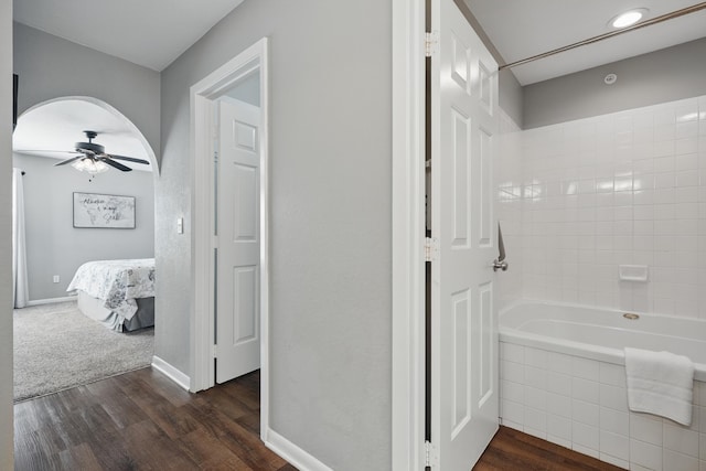 ensuite bathroom featuring wood finished floors, ceiling fan, and baseboards