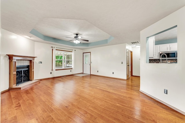 1240 Tyler Ln, Nixa, MO 65714 - unfurnished living room with a ceiling fan, a raised ceiling, light wood-style floors, and baseboards