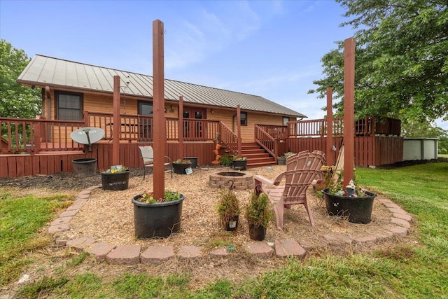 6203 County Road 1750, West Plains, MO 65775 - rear view of house with a standing seam roof, an outdoor fire pit, a deck, metal roof, and a yard
